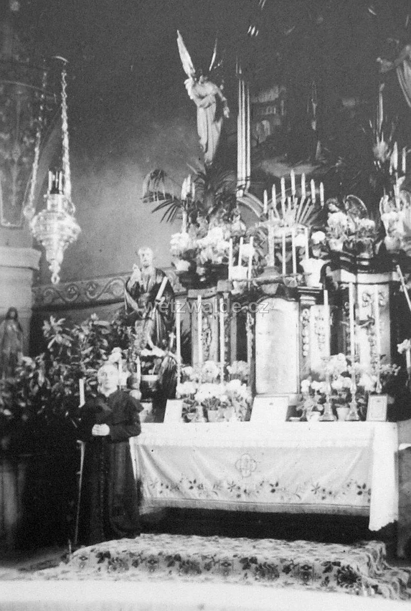 Historické foto interiéru kostela – hlavní oltář s panem farářem, před rokem 1945.